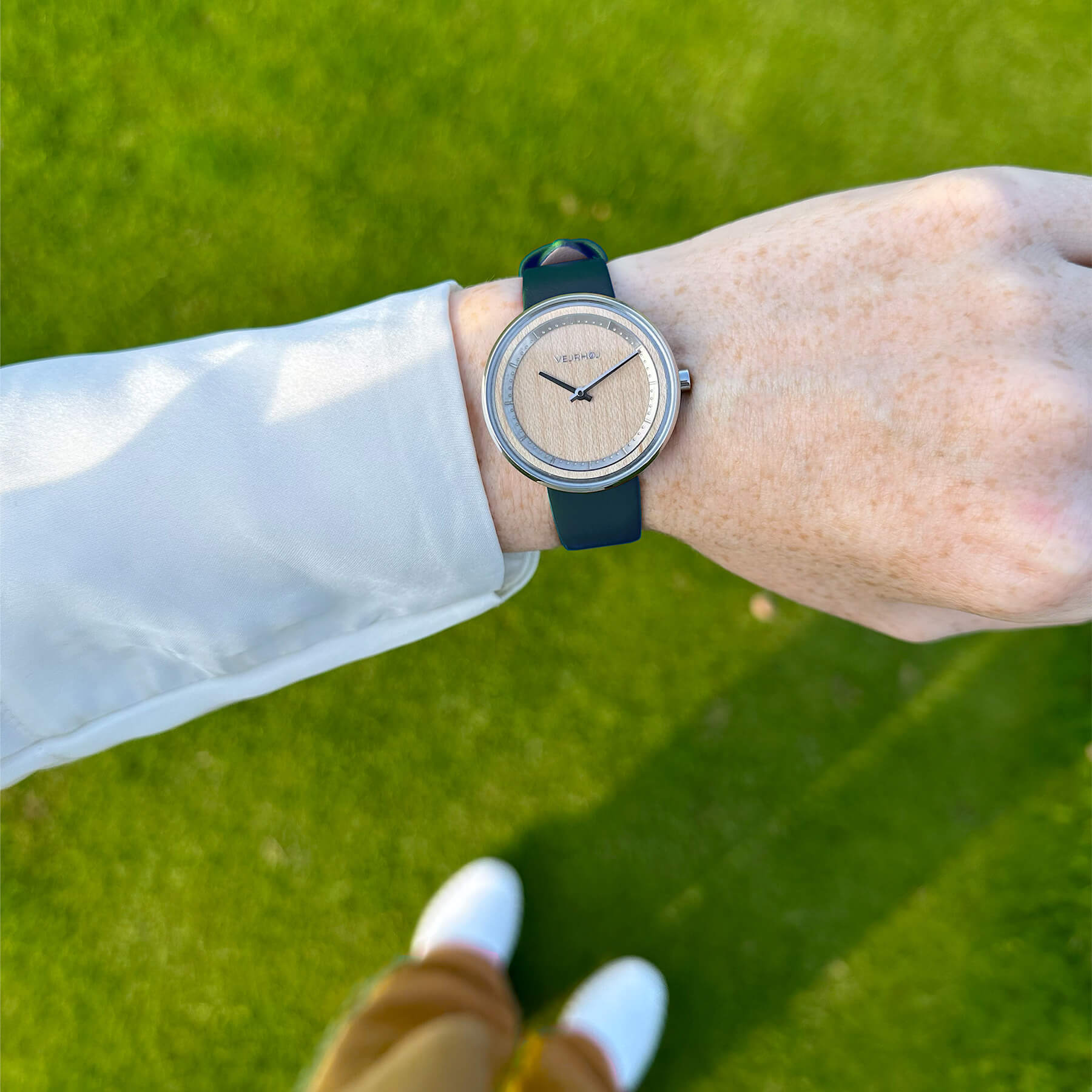 wood watch with a green strap on a female hand