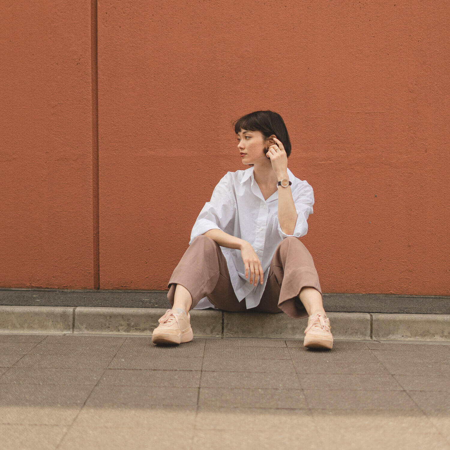 Young woman looking away wearing a wooden watch and white shirt